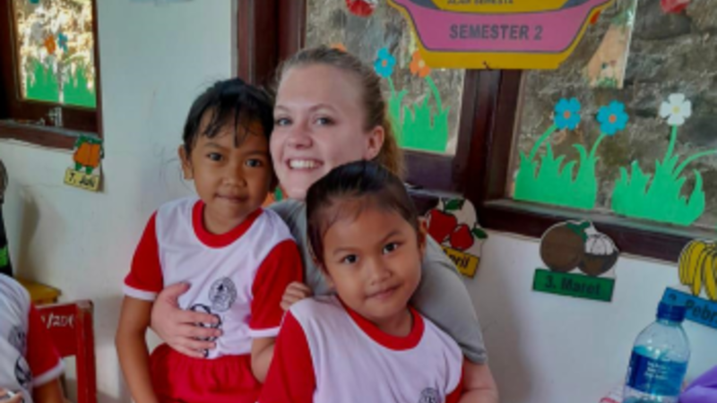 Lynn in de Indonesische kleuterschool met twee kleuters in haar armen