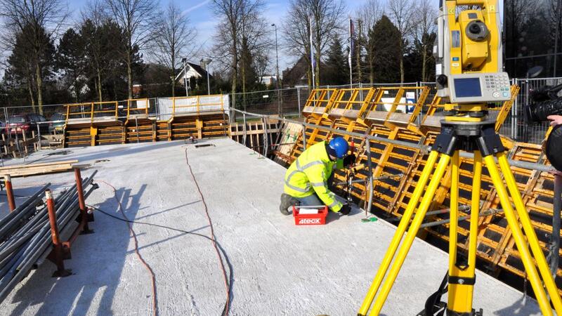 Een bouwvakker in een gele veiligheidsjas is aan het werk op de bouwplaats