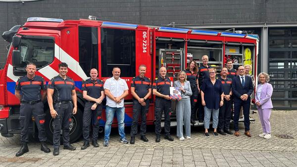 Ellen Marks poseert met een groep brandweermannen voor een bluswagen
