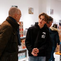 Een student helpt een klant in de winkel