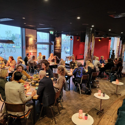 Aanwezigen zitten gezellig aan tafeltjes in het theater café in de Deventer Schouwburg